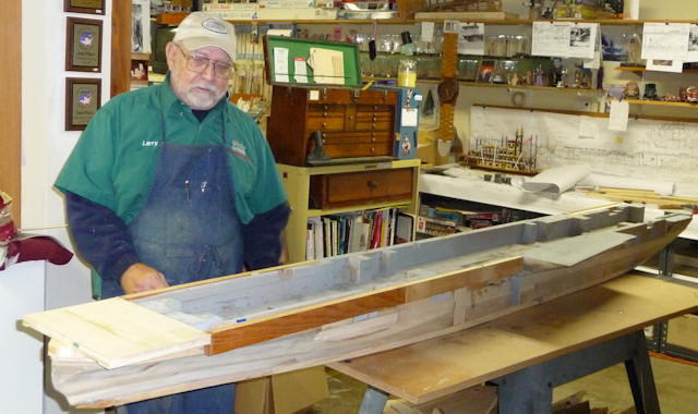 Master builder next to hull of USS Oriskany model
